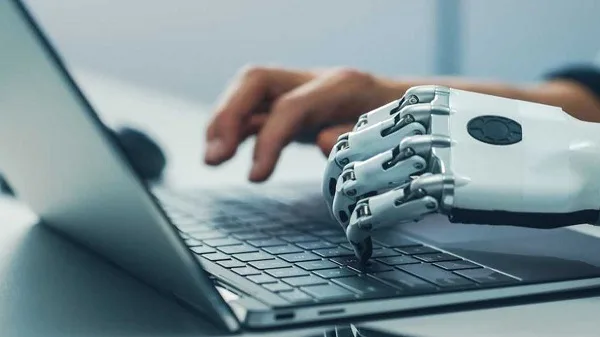 A robot hand typing on a computer Description automatically generated